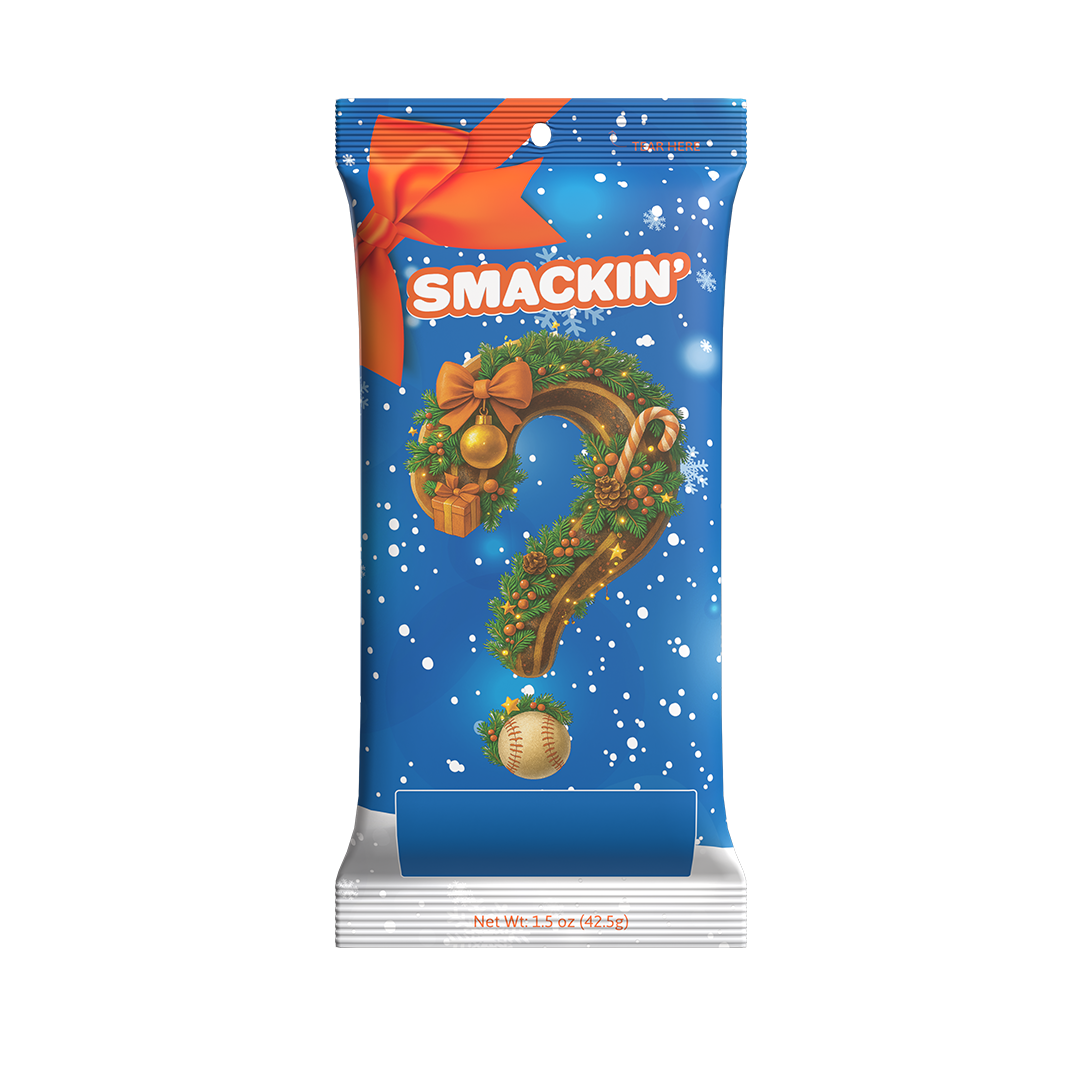 Digital illustration of a 'SMACKIN'' product package, bright blue with falling snowflakes and an orange bow, featuring a festive Christmas wreath forming a question mark adorned with a gold ornament and candy cane, with a baseball as the dot on a snowy foreground