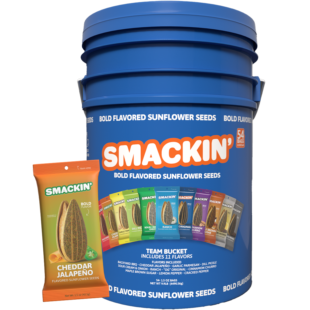 Smackin' Bold Flavored Sunflower Seeds Team Bucket, a large blue container holding 54 bags with 11 distinct flavors like Cheddar Jalapeño and Dill Pickle, shown next to an individual orange bag of Cheddar Jalapeño seeds