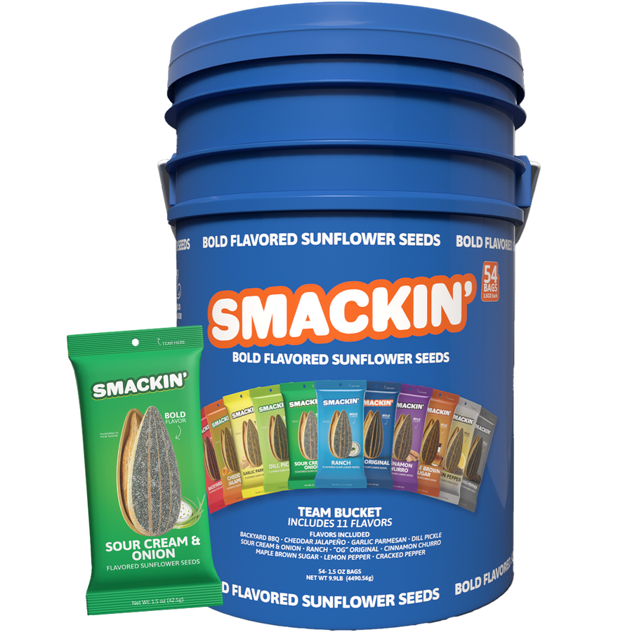 Digital product photo of a large blue Smackin' Bold Flavored Sunflower Seeds team bucket containing 54 bags, featuring a front label showing a vibrant row of flavor bags including Sour Cream & Onion and Ranch, with a prominent green Sour Cream & Onion bag in the foreground