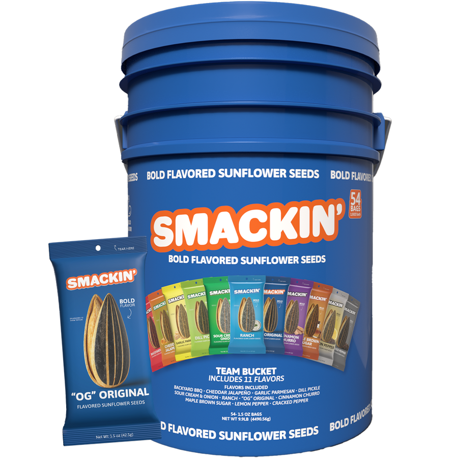 Product photography of a large royal blue Smakin Bold Flavored Sunflower Seeds Team Bucket containing 54 bags and showcasing 11 colorful flavor pouches including Backyard BBQ, Dill Pickle, and Ranch, with a smaller blue OG Original bag standing beside it