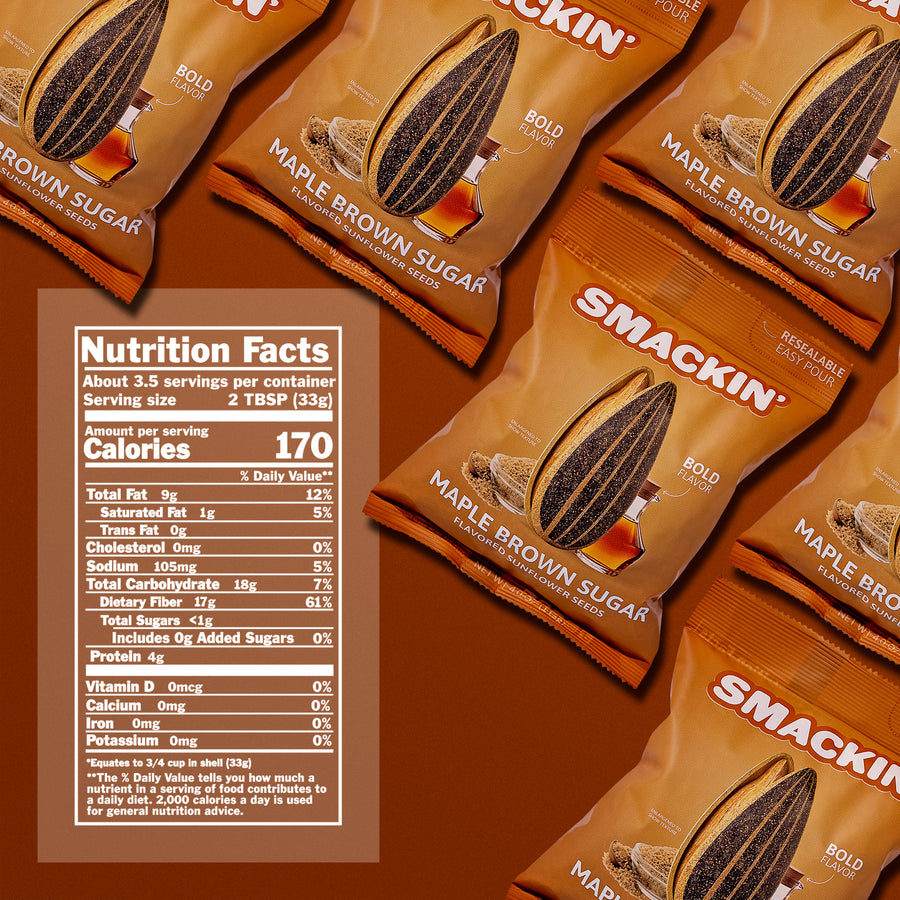 Product photography of multiple Smackin' Maple Brown Sugar Flavored Sunflower Seeds bags on a warm brown surface, showcasing their distinctive brown and orange packaging with an illustrated sunflower seed, maple syrup, and brown sugar, alongside a visible nutrition facts label highlighting 170 calories